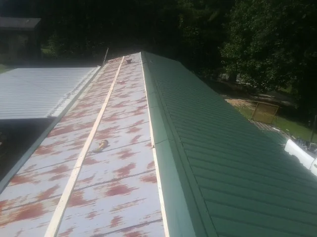 Old rusted panels beside newly installed green metal roofing — Wind Damage Roof Repair by Roofing Brothers in Hazen