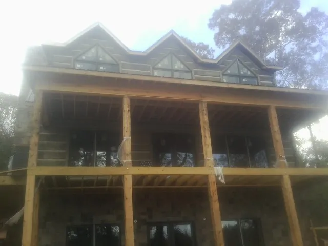 Dormers and porch framing on a large log home under construction — Roof Coating work by our crew in Hazen
