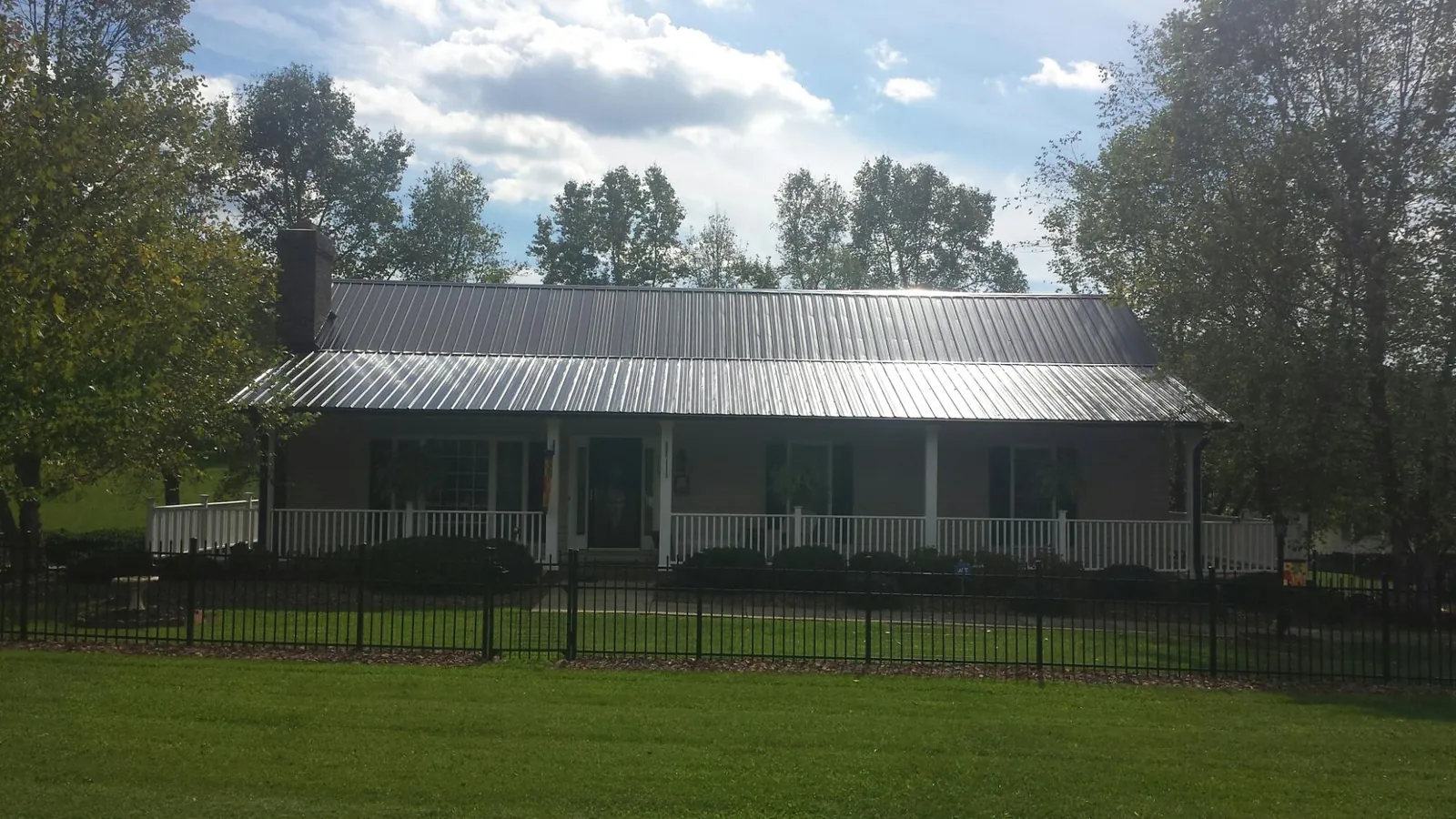 Gray metal roof on a brick ranch with a full width front porch — Gutter Guard Installation work by our crew in Hazen
