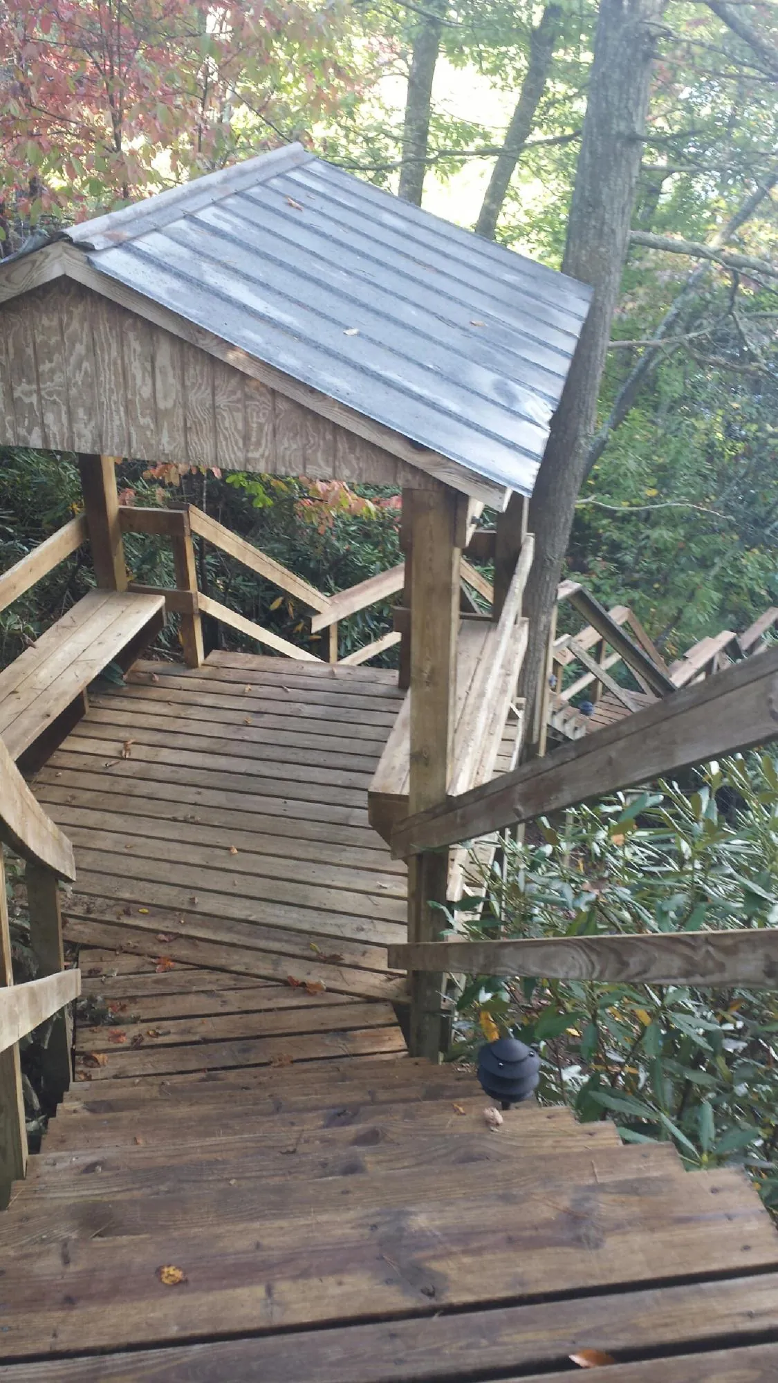 Metal roofed shelter over wooden steps on a wooded walkway — Skylight Repair & Installation work by our crew in Hazen